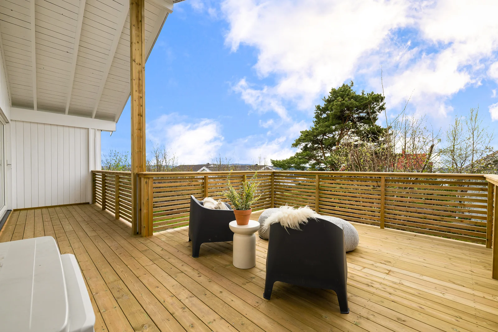 Overbygd treterrasse med spileverk, sitteplasser og utsikt mot hagen